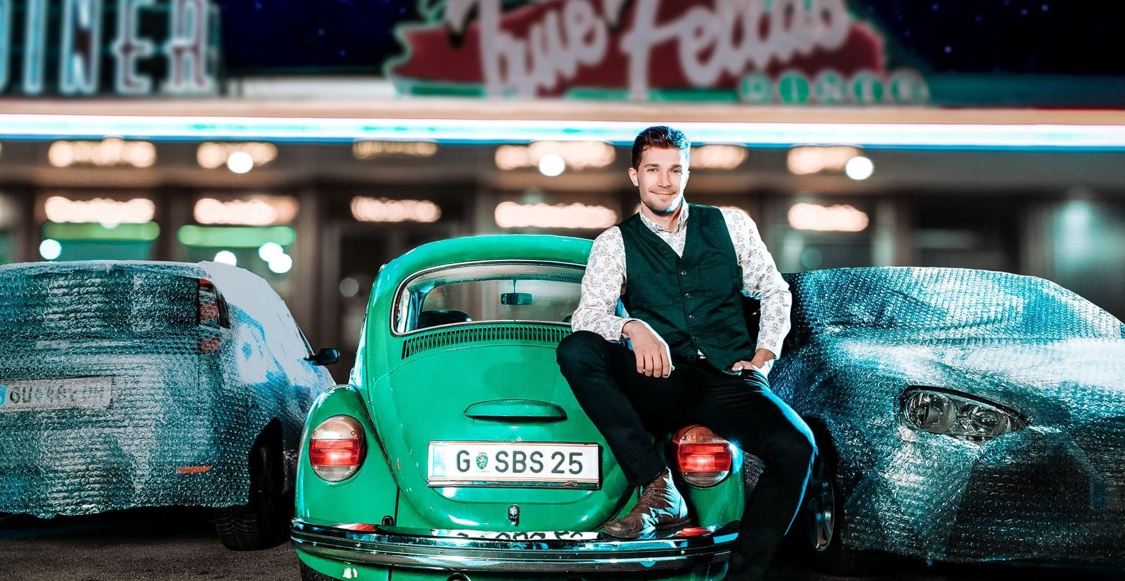 Mann lehnt an einem VW-Käfer