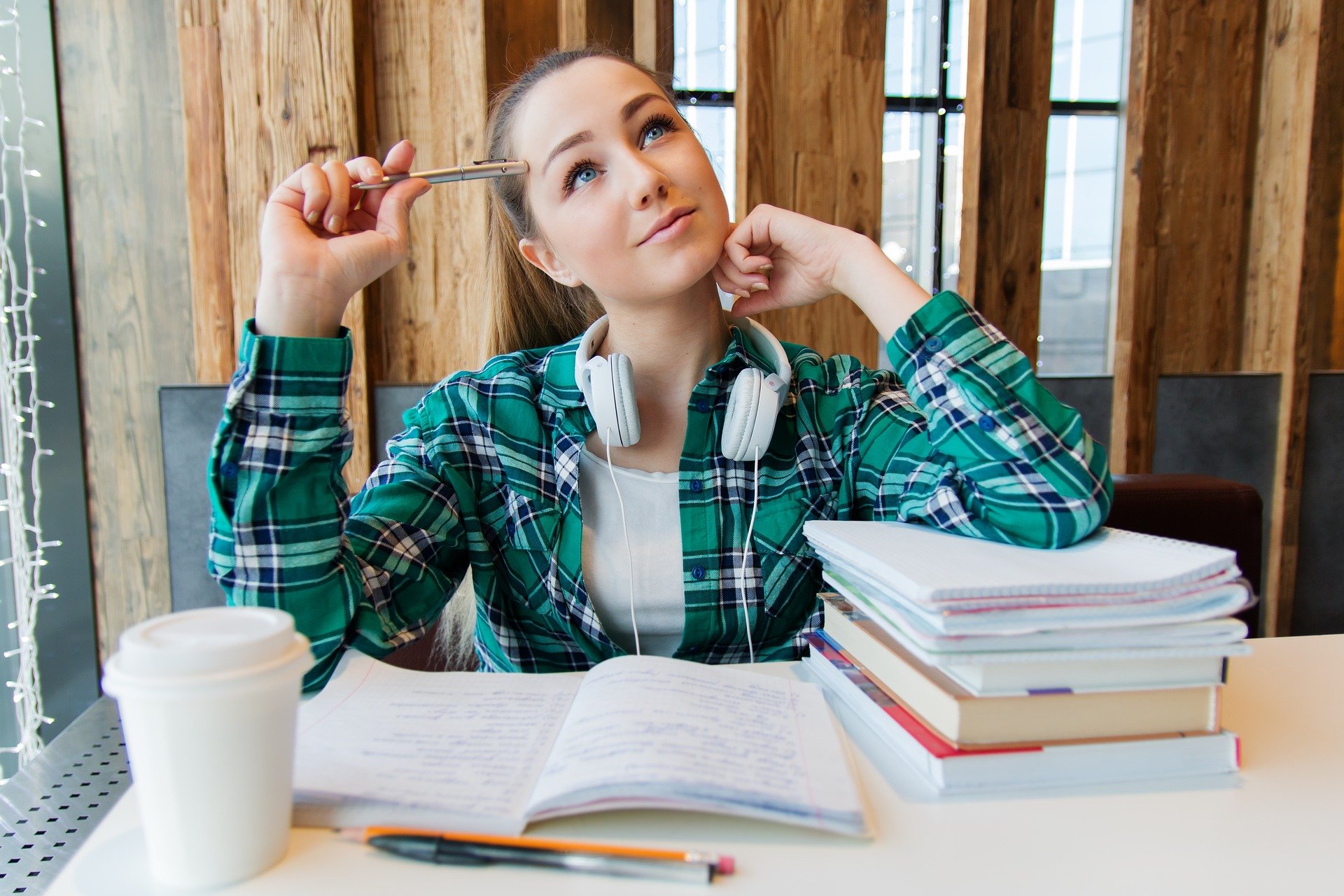 Junge Studentin sitzt auf einem Tisch voller Bücher