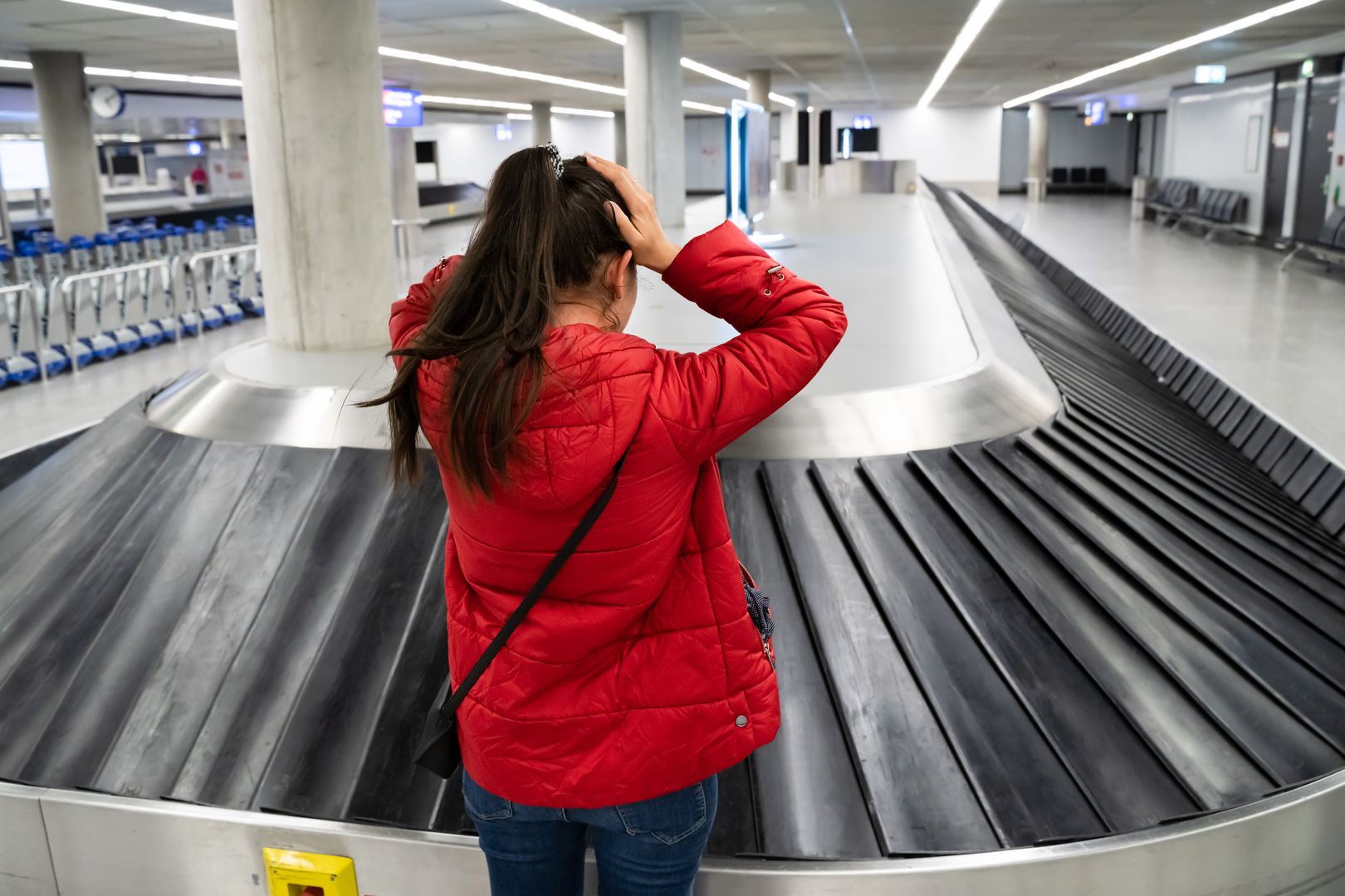 Frau vor leerem Gepäckband am Flughafen