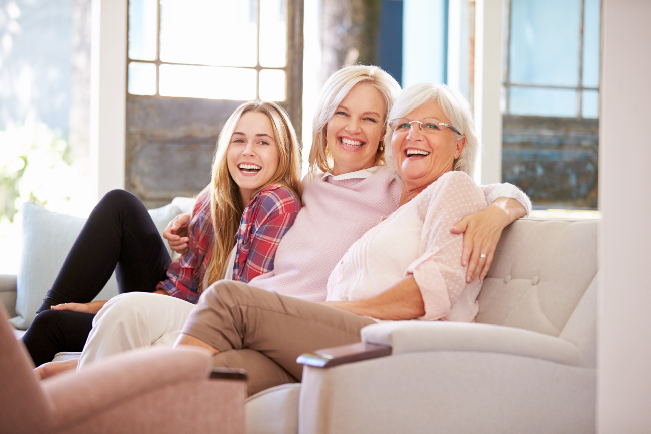 3 Frauen sitzen lachend am Sofa